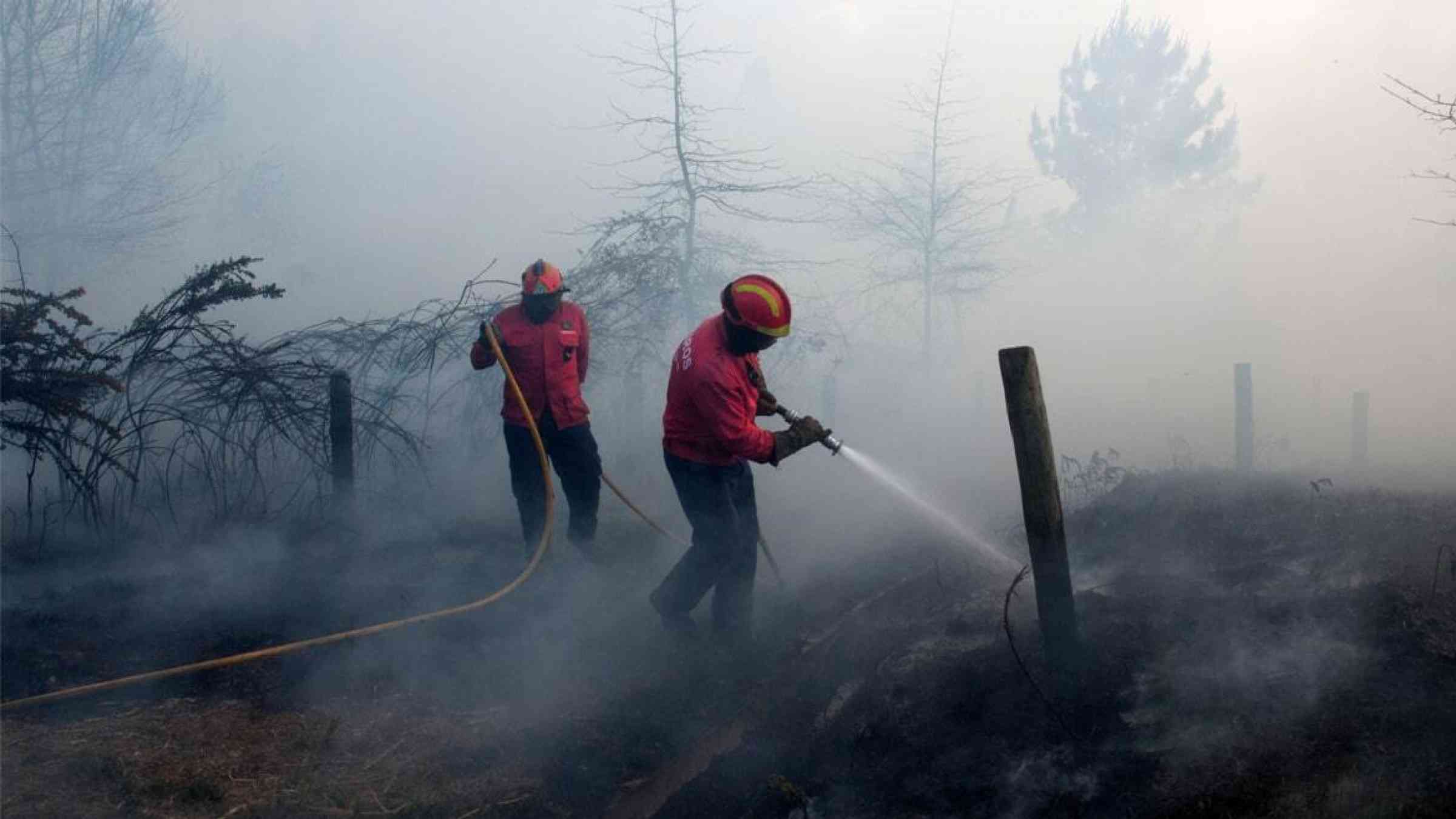 Portuguese firefighters extinguish a wildfire outside Guimarães