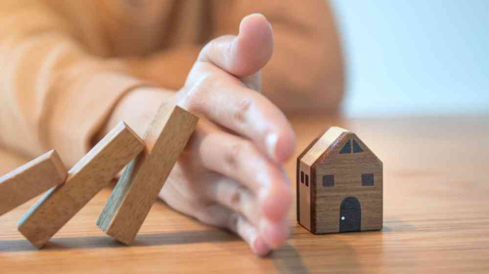 Hand stopping wooden blocks from falling on a house