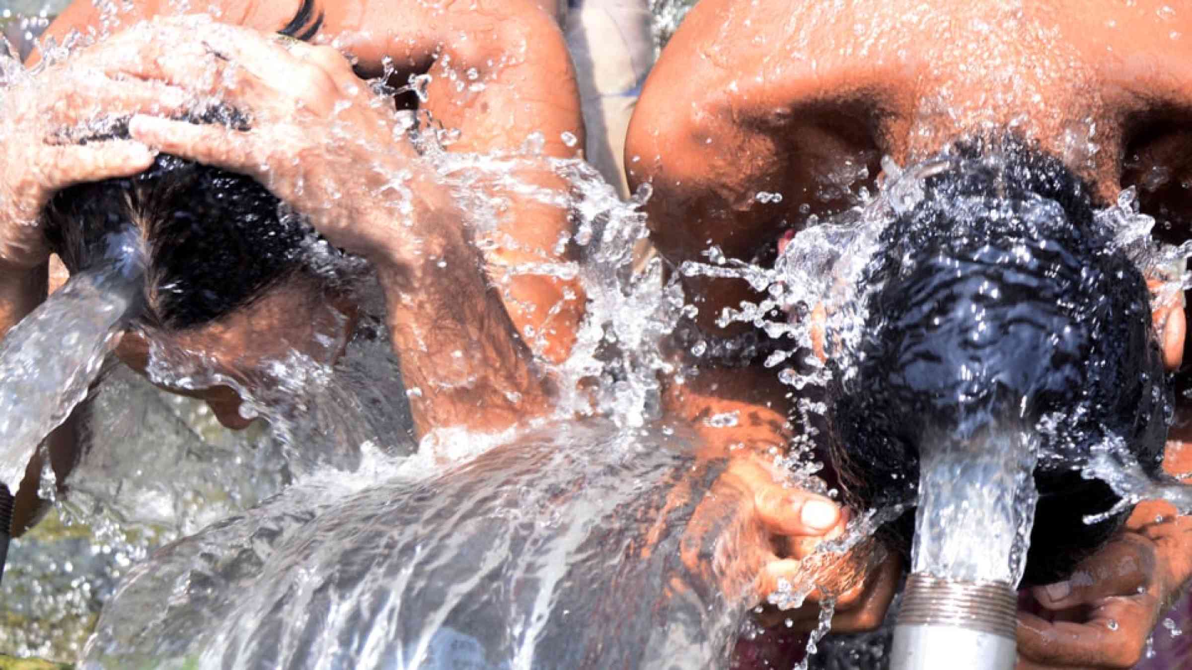 People taking a bath at a municipal water source to cope with the heatwave in India, 2015