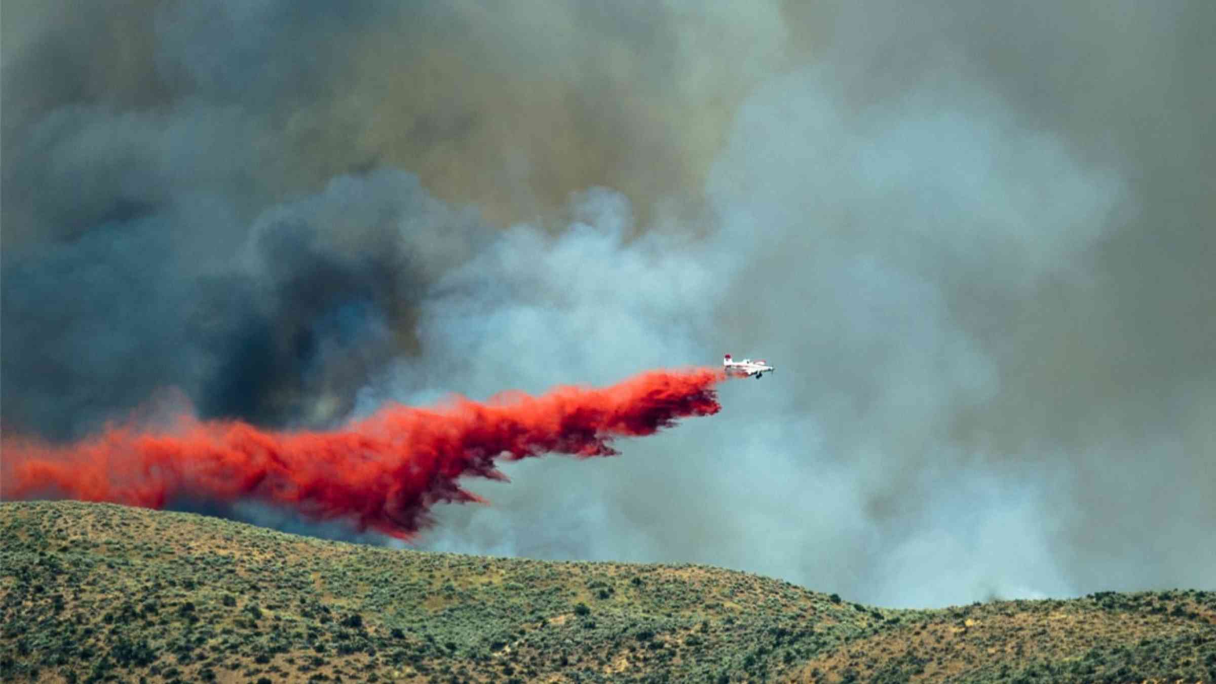 Aircraft dropping fire retardant as it battles a wildfire
