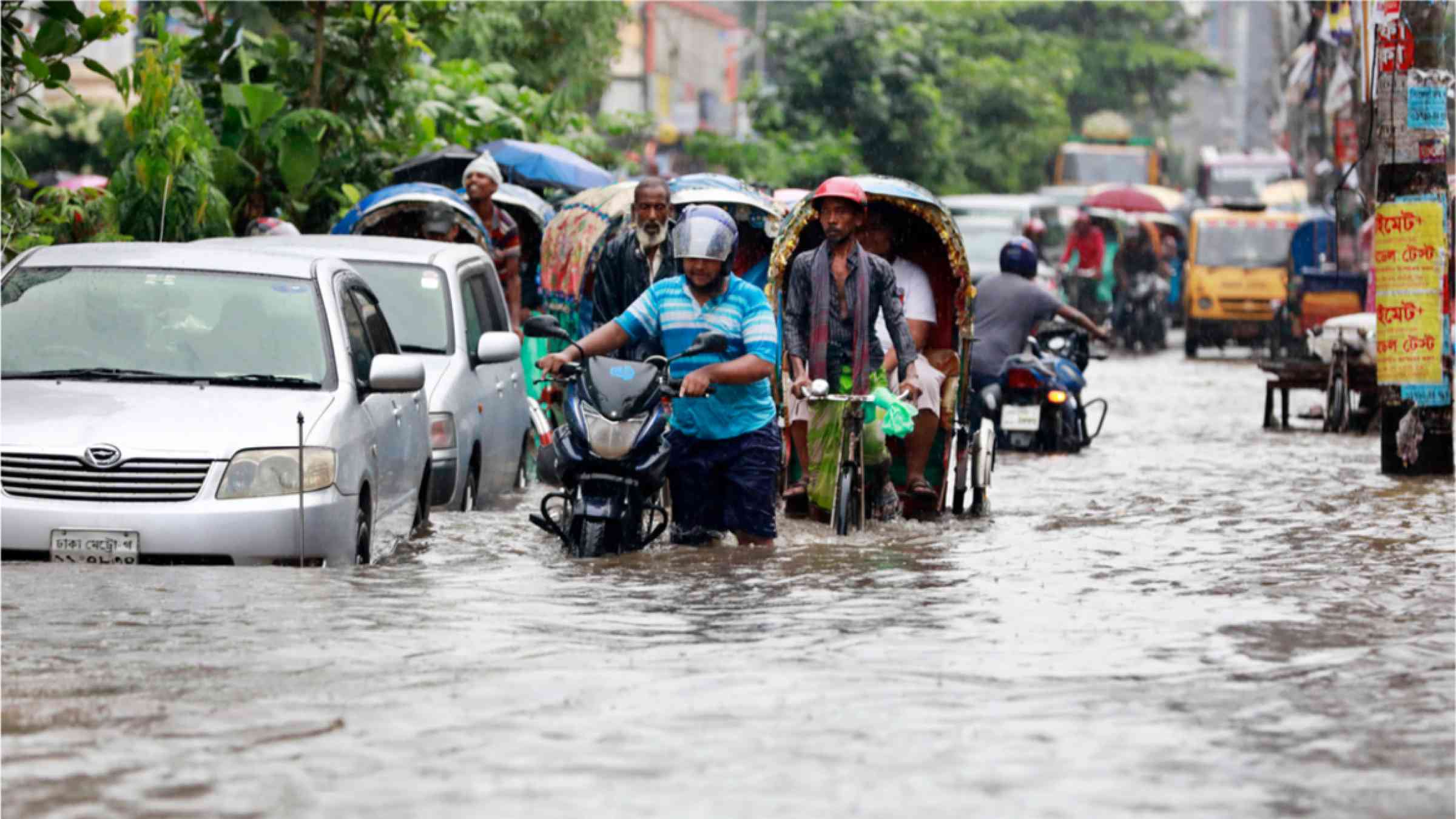 Dhaka residents wade in floodwater after heavy rains