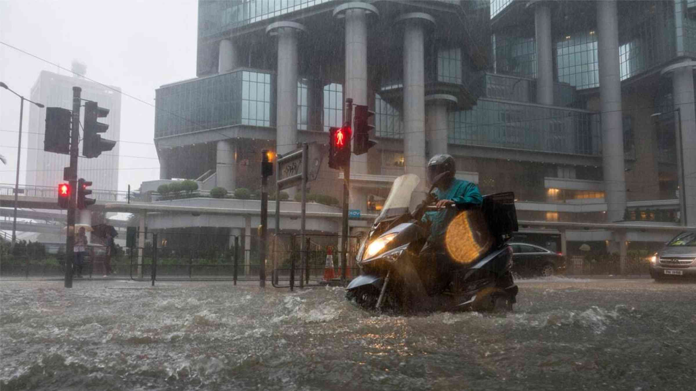A motorcyclist drives through an inundated street during a rainy day in Hong Kong