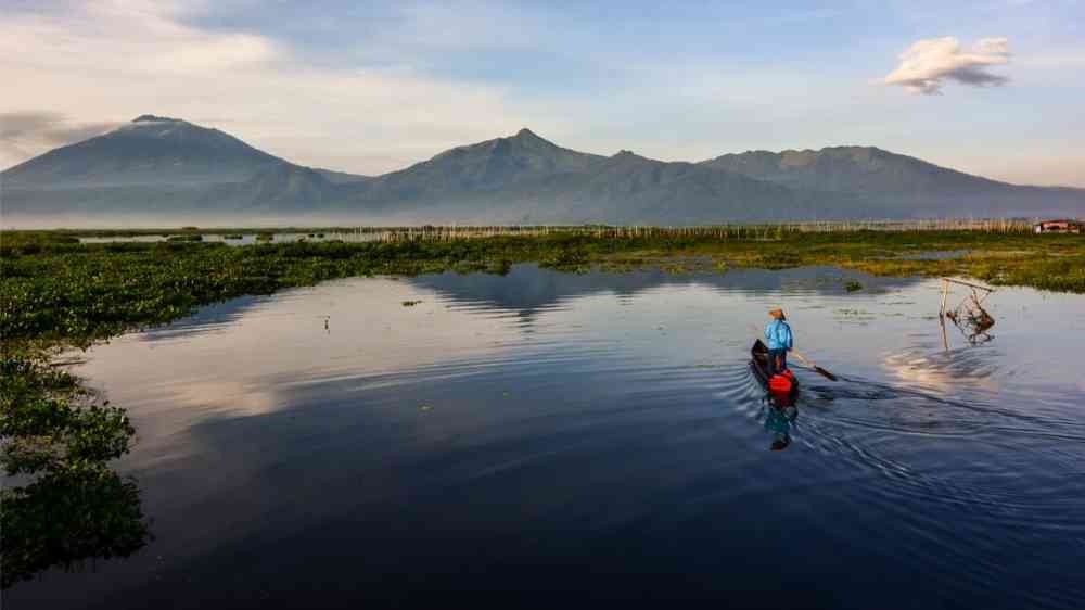 A villager crosses peat-rich Lake Rawa Pening by boat in Indonesia