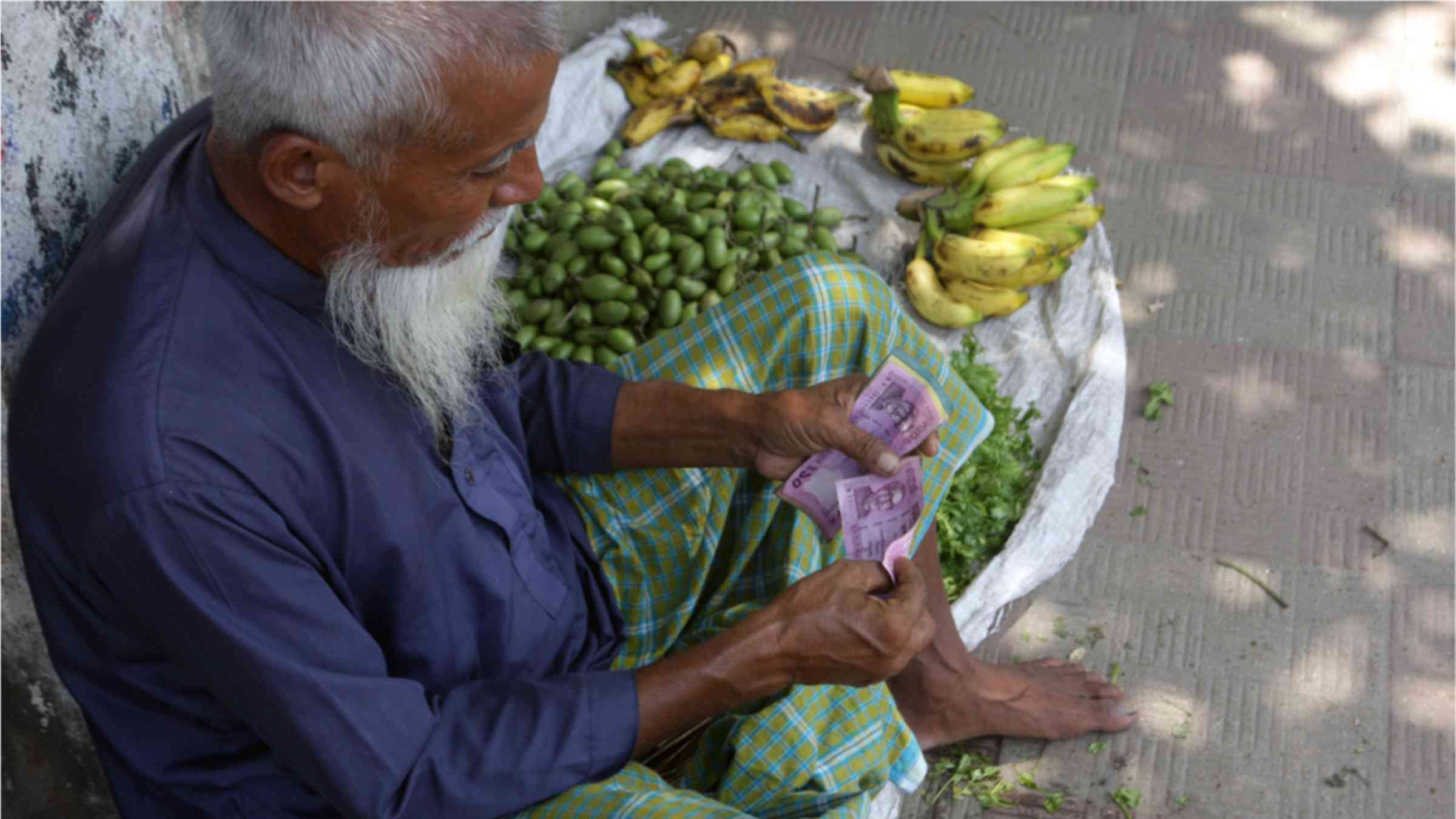 Asian old man with white beard sales fruit in the streets to earn money.