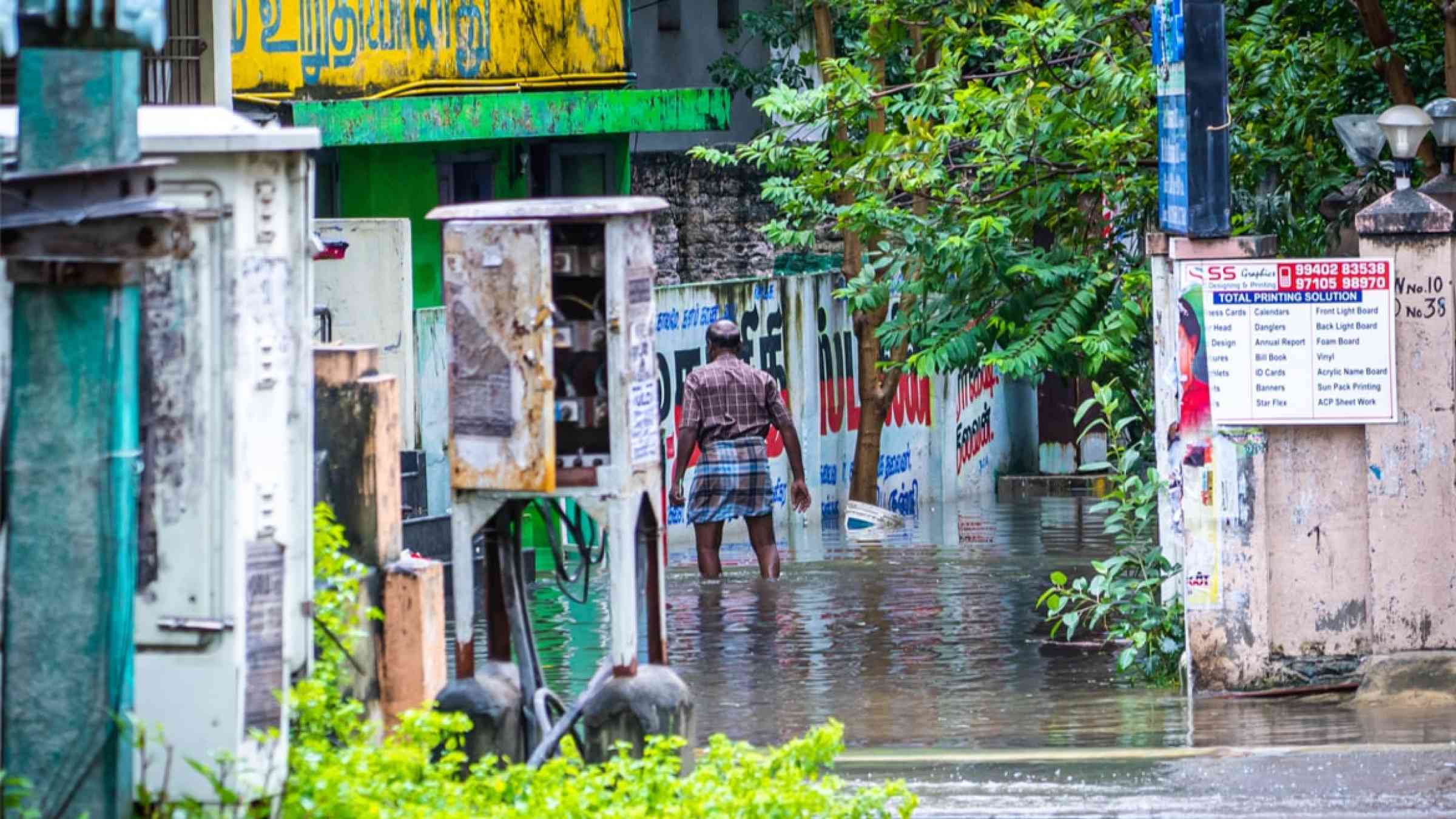 An unknown man walks on a flooded street following cyclone Nivar in Chennai, India (2020))