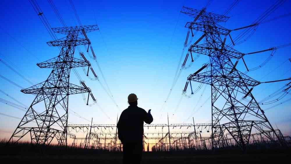 An engineer observes transmission lines overhead