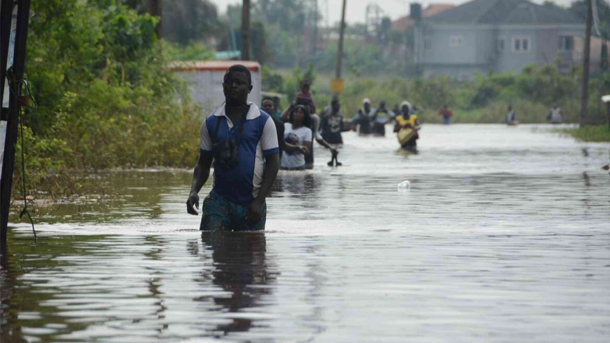 A man wades along a flooded street in Wawa, Ogun State, Nigeria