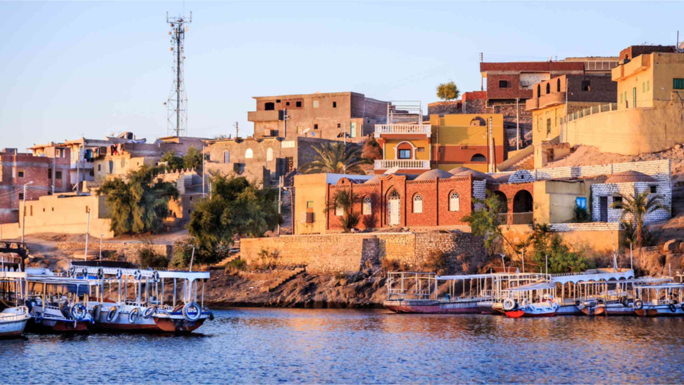 ooden boats carrying passengers sailing along the Nile along the temple of Philae in Aswan, Egypt, North Africa