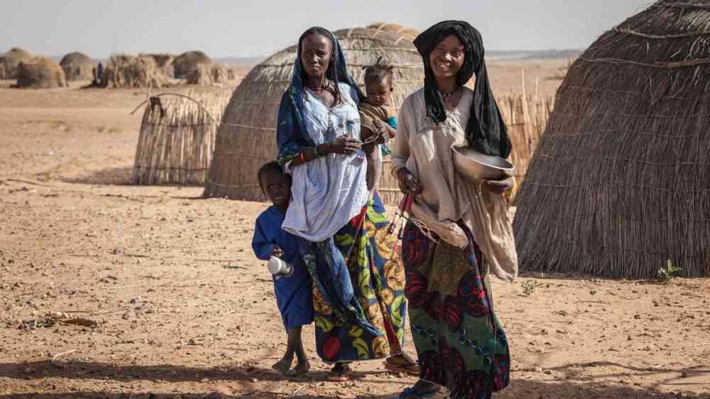 African family from the Djerba tribe in traditional colorful clothes in front of their house in Niger (2013)