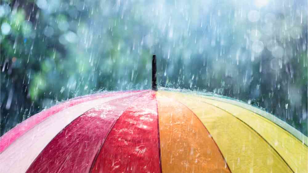 Rain pouring down on an umbrella in rainbow colors.