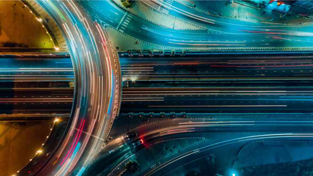 Highway with cars rushing over it at night.