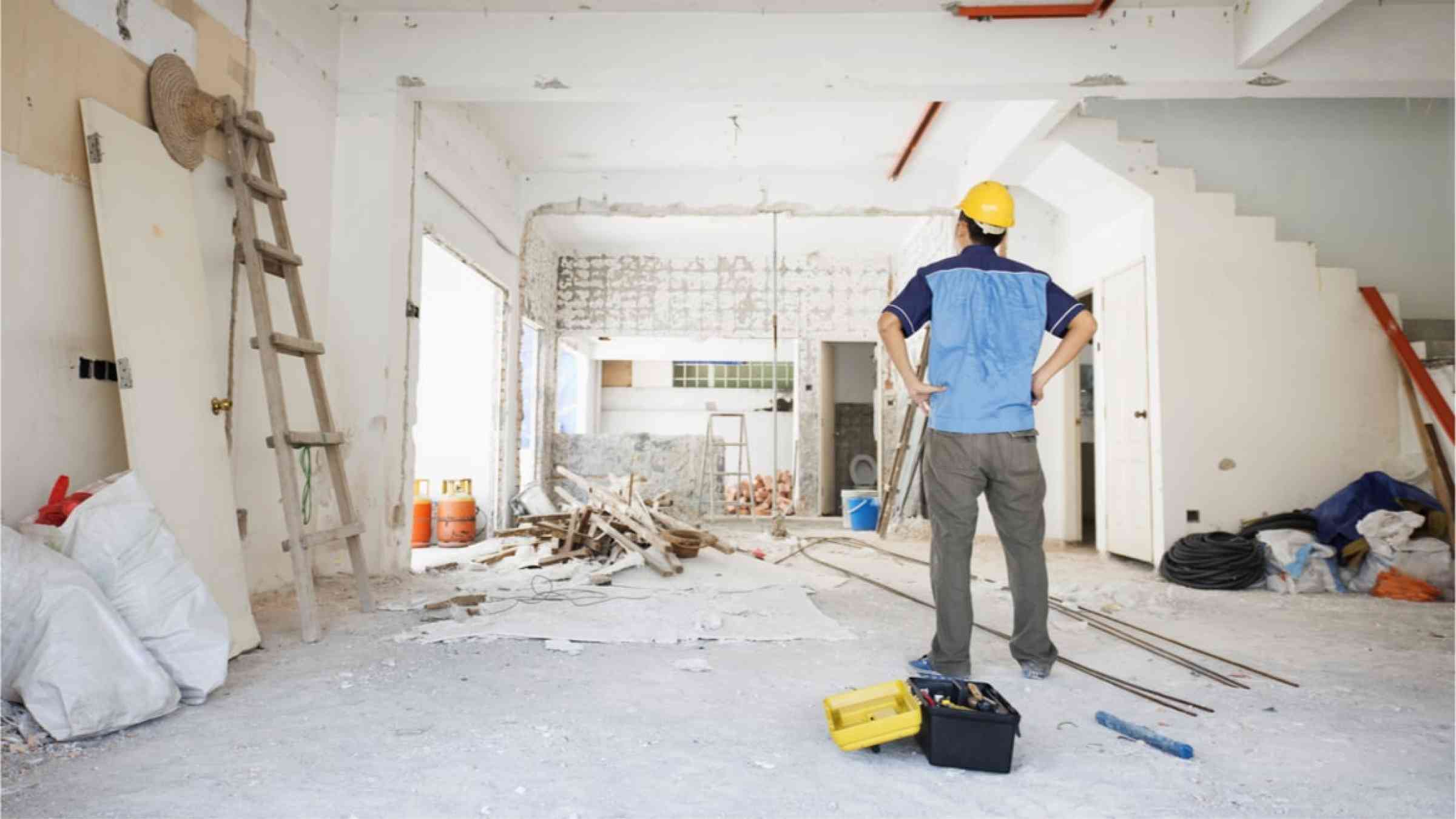 A construction working standing in a room of a house that is being renovated.