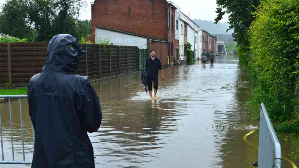 Man walking barefoot in a flooded street in Wilsele, Vlaams-Brabant, Belgium (2021)