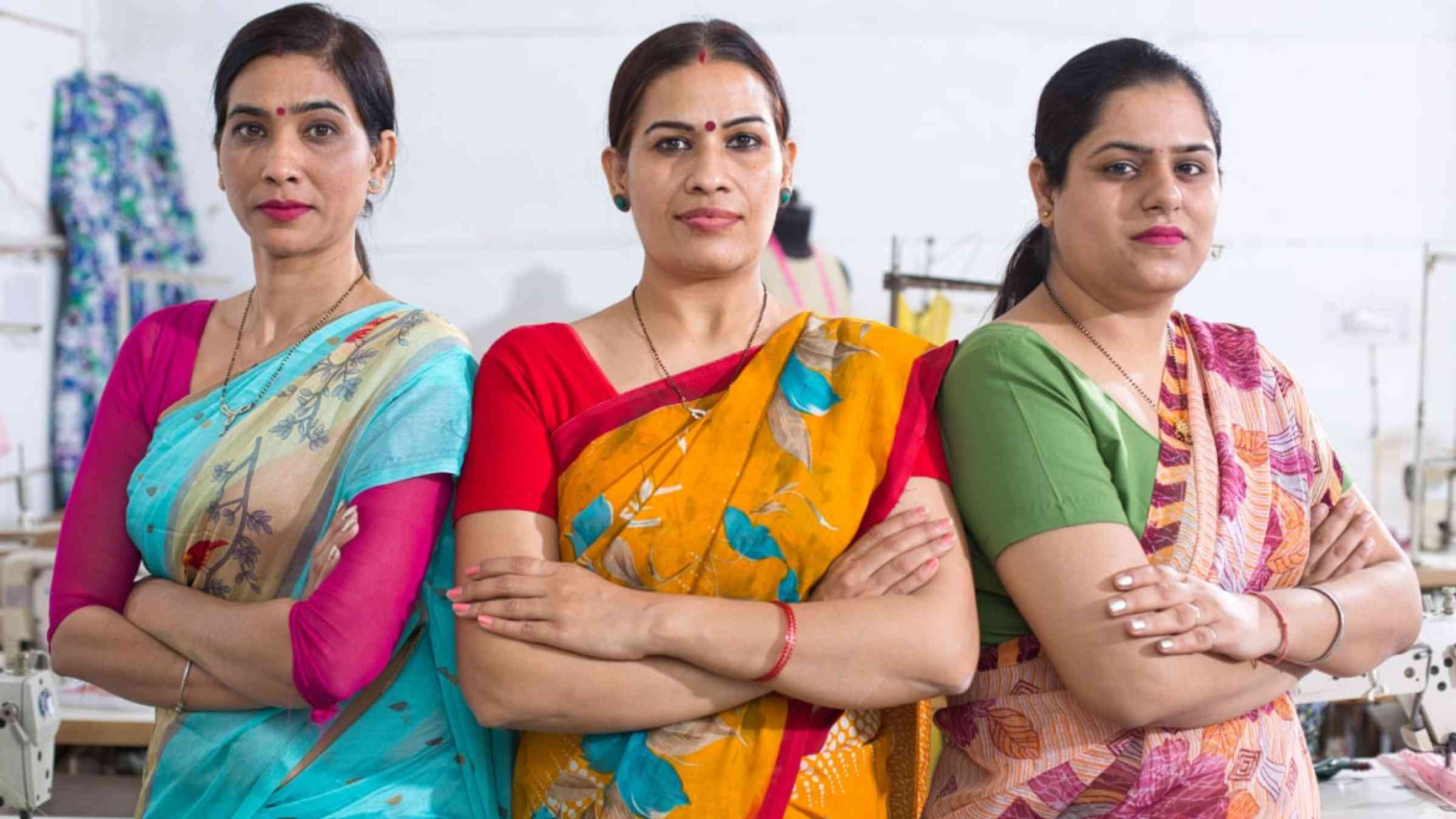 Three Indian female textile workers standing together in solidarity at factory