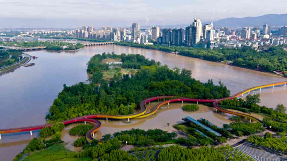 Review with a colourful bridge going over it. Medium sized city in the background