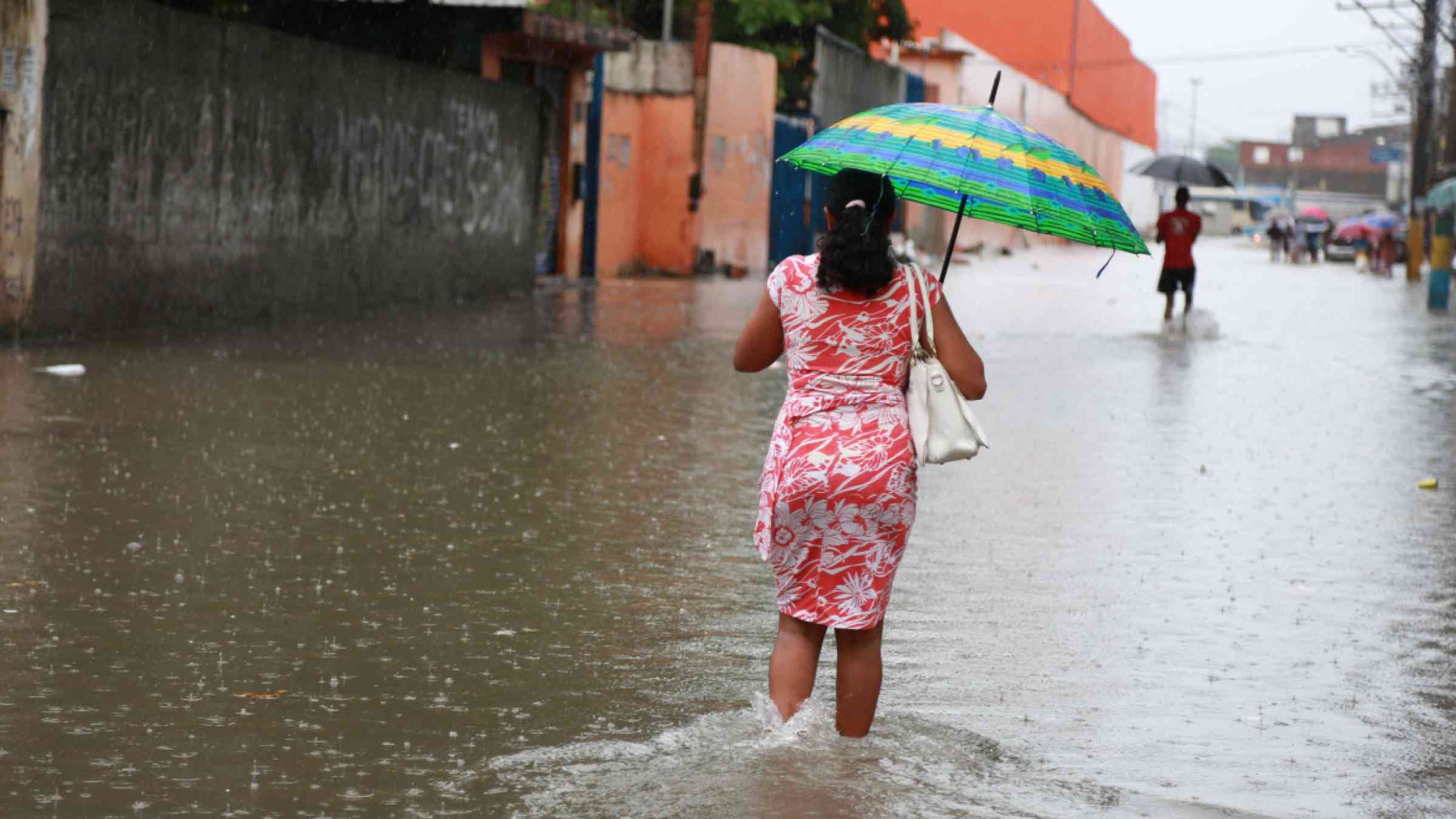 Woman with an umbrella walking through a flooded street in city of Salvador, Brazil in 2015