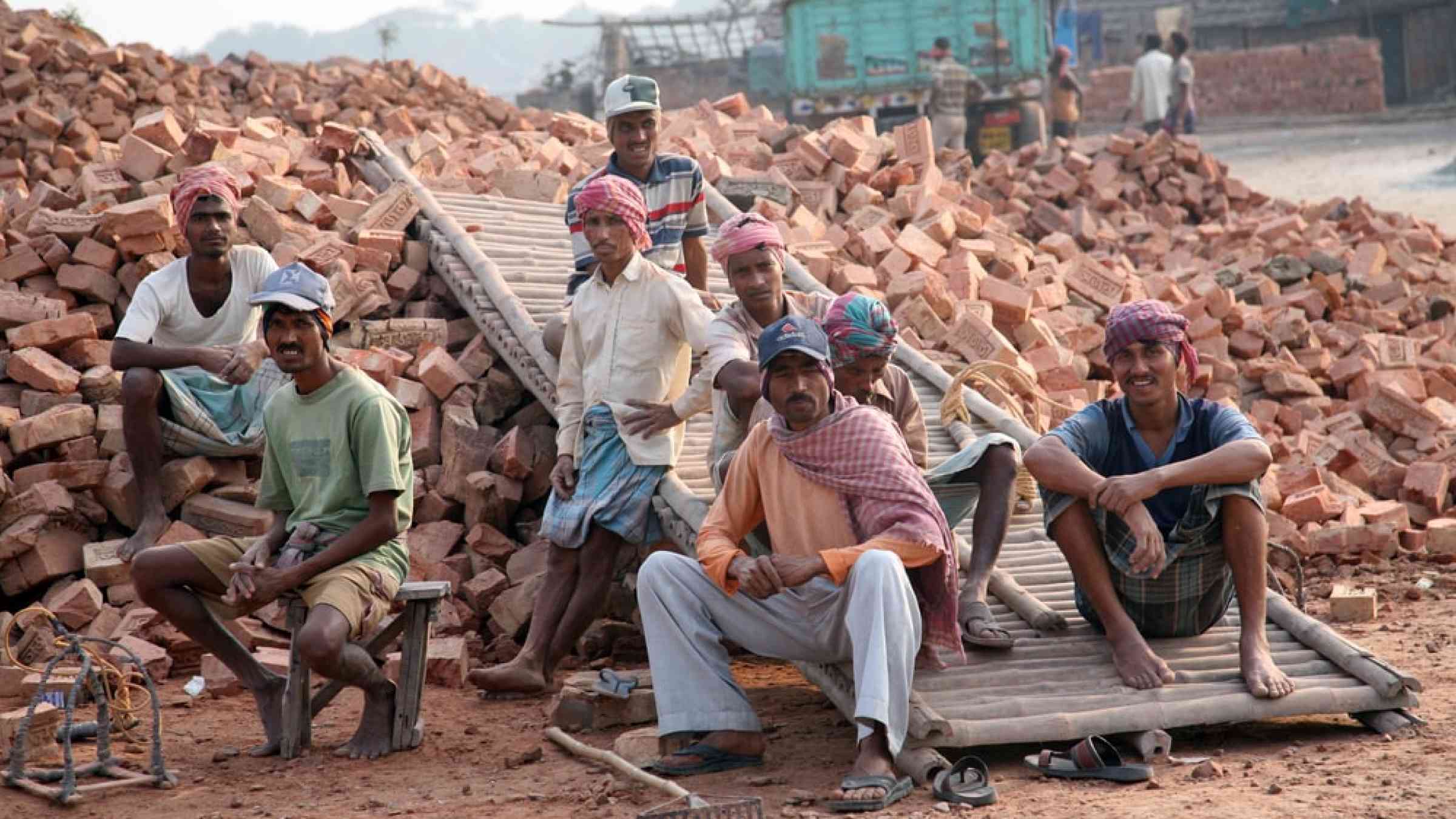 Brick field workers rest after hard work, wearing just baked brick from the kiln in truck