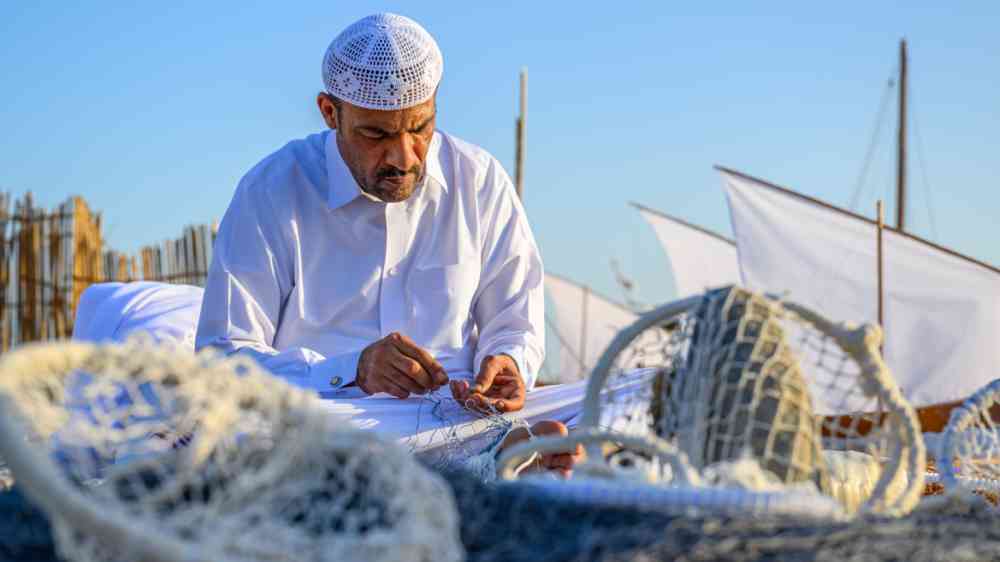 An Arab man repairs a fishing net during the Sailing Bearings Festival in Katara Village near Doha, Qatar.
