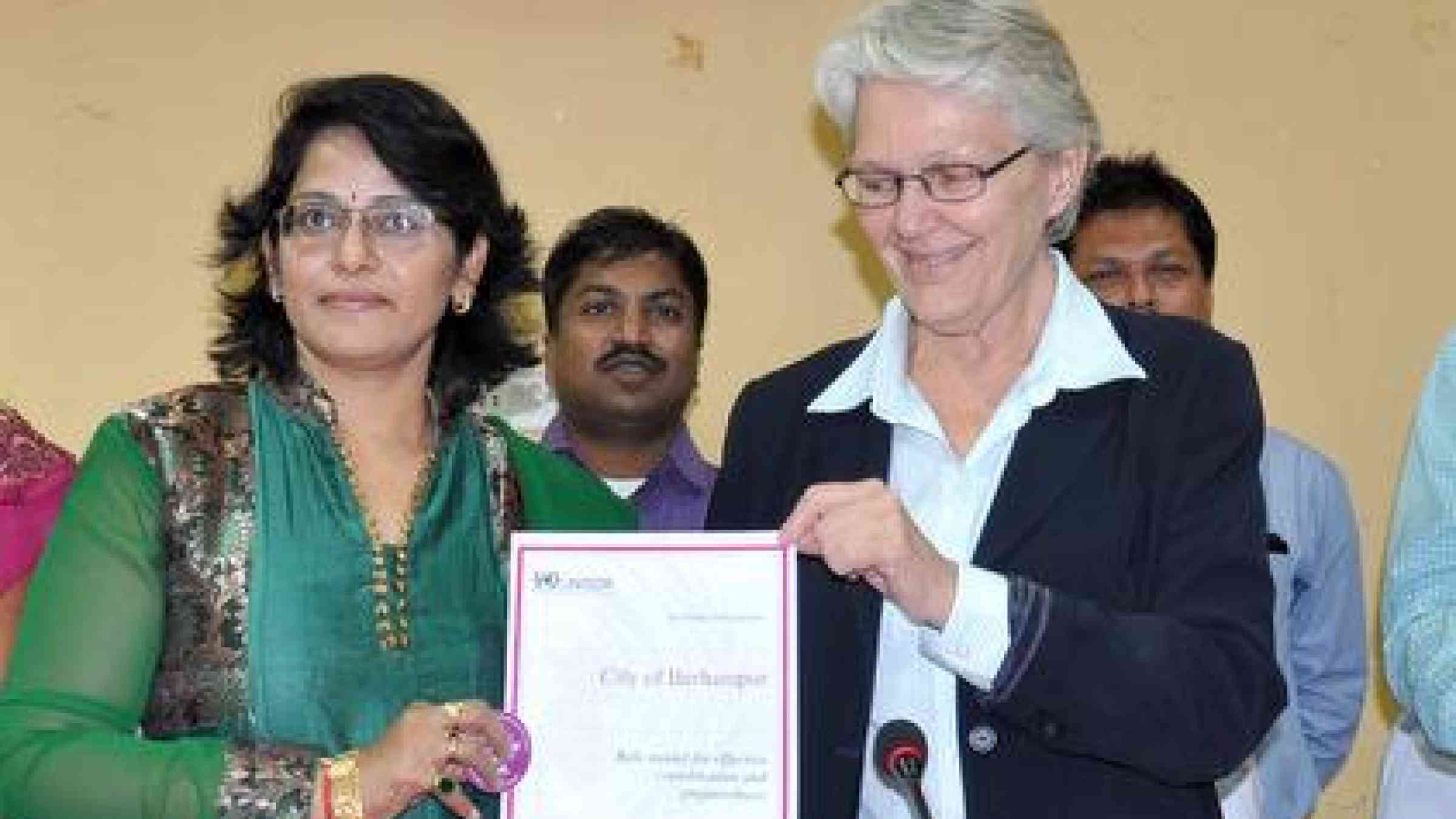 The Mayor of Berhampur, Ms K. Madhavi (left) receives a certificate of recognition from UNISDR Head Ms Wahlström.